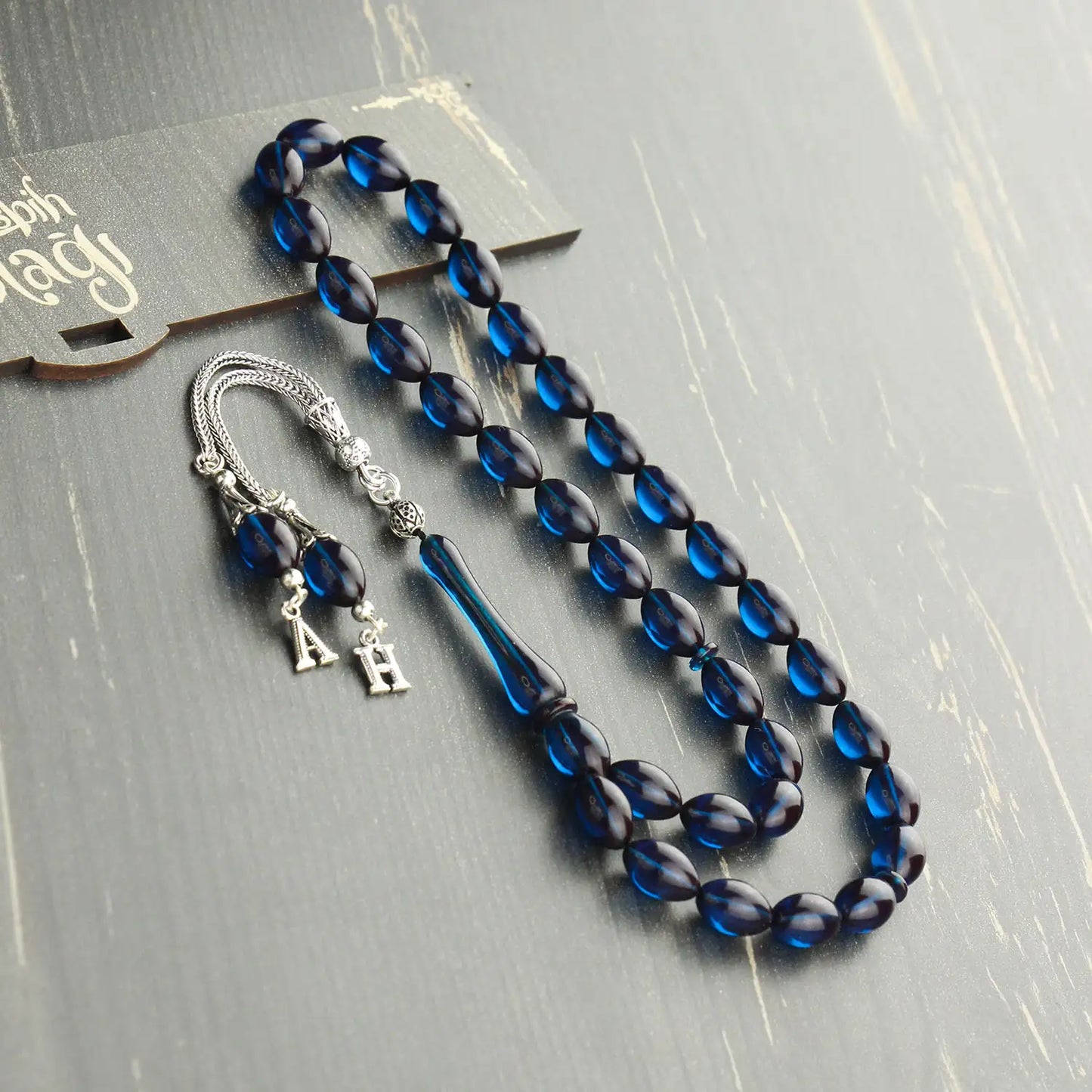 Kişiye özel mavi ateş kehribar tesbih, harfli gümüş püsküllü tasarım.