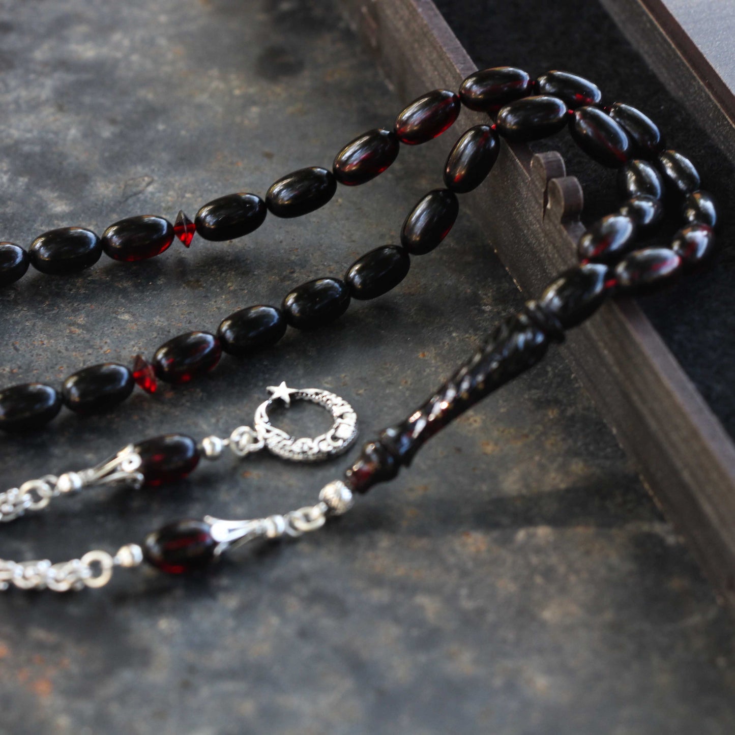 مسبحة كهرمانية باللون الأحمر والأسود مع شرابات فضية ومكتوبة في صندوق مخصص